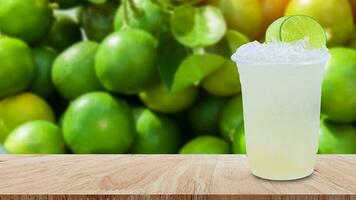 cool fraîchement fabriqué limonade dans une Plastique tasses avec écrasé la glace et citron tranches sur en bois table avec vert citrons verts brut citron pendaison sur citron arbre Contexte photo