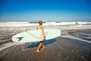 gars en marchant avec planche de surf sur une rive photo