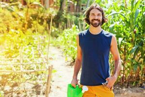 Beau barbu agriculteur en portant une arrosage pouvez dans une jardin photo