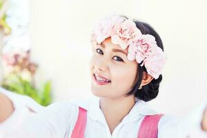 selfie de une jolie asiatique fille portant floral Bandeau photo