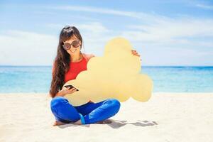 nuage espace de rangement concept. femme en portant papier nuage icône sur le plage photo