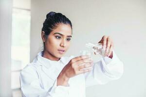 Jeune Indien biotechnologie science étudiant verser l'eau dans une ballon pour une scientifique expérience photo