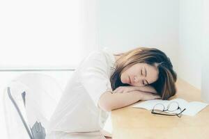 portrait de asiatique femme en train de dormir sur le bureau après sa travail au fil du temps. photo