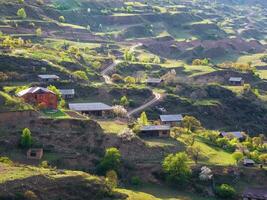 haute montagne village dans daghestan. Maisons sur une vert Montagne terrasse. route à travers le vallée. aérien voir. photo