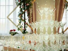 proche en haut de vide du vin des lunettes sur une table sont une pyramide. magnifique mariage la cérémonie à l'intérieur. photo