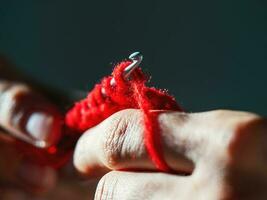 fermer crochet avec rouge la laine fil sur une foncé Contexte. photo
