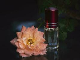 concentré parfum dans une mini bouteille avec rose parfumé thé Rose sur le noir Contexte. photo