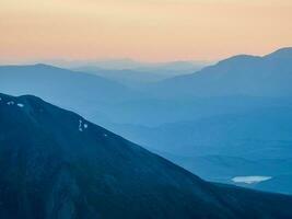 magnifique Montagne paysage avec de le coucher du soleil ciel de rose Orange lilas violet magenta couleurs. coloré lisse Aube ciel pente. la nature Contexte de lever du soleil. incroyable Matin paradis. photo