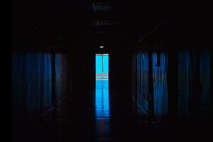 bleu lumière à le fin de une foncé couloir. fin de foncé tunnel avec la magie bleu lumière. vide foncé couloir dans hôpital laboratoire. photo
