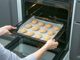 le cuisinier cuit au four biscuits dans le four dans le cuisine. cuisson courtb photo