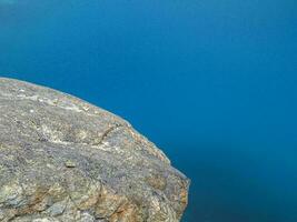 minimaliste la nature Contexte de pierreux bas dans turquoise transparent l'eau de glacial Lac dans lumière du soleil. ensoleillé toile de fond avec beaucoup des pierres dans vert clair l'eau de glacier lac. photo