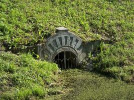 l'eau couler dans le étang. le entrée est fermé par une fort métal gril photo