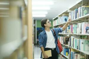 étudiant choisir et en train de lire livre à bibliothèque. photo