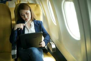 affaires femme travail sur tablette tandis que séance dans avion. photo