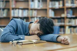fatigué épuisé étudiant en train de dormir à bibliothèque. photo