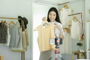 Jeune asiatique femme d'affaires mode blogueur montrant tissu avec souriant affronter. photo