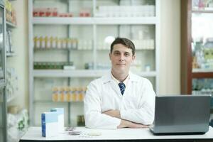 Masculin pharmacien travail dans moderne pharmacie en utilisant portable. photo