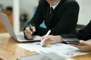 les hommes d'affaires fonctionnement, discuter, en cours d'analyse en utilisant portable et graphiques. photo