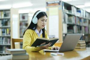 étudiant séance et en train d'étudier avec portable à bibliothèque. photo