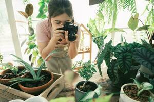 souriant Jeune femme prise téléphone intelligent image de plante dans une petit magasin photo