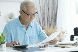 Sénior homme calculateur les taxes à maison. photo