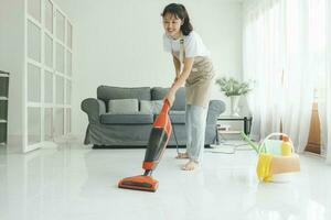 Jeune femme nettoyage maison avec vide nettoyeur. photo