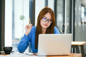 Jeune femelle Université étudiant les usages une ordinateur à accès le l'Internet pour en ligne apprentissage. photo