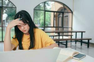 sérieux asiatique femelle étudiant en train de lire livres pour examen préparation photo