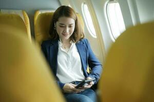 affaires femme dans une avion, travaux sur en utilisant sur téléphone.casque photo