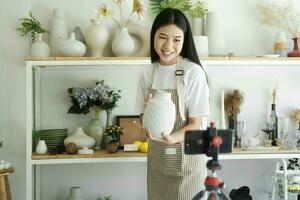 Jeune asiatique femme d'affaires mode blogueur montrant céramique des produits avec souriant affronter. photo