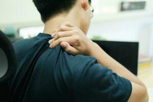 Jeune asiatique homme avec Bureau syndrome avoir problème avec partie de corps bras épaule tête cou dos. photo