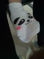 photo de une de bébé pied dans une chaussette avec une mignonne Panda visage sur il