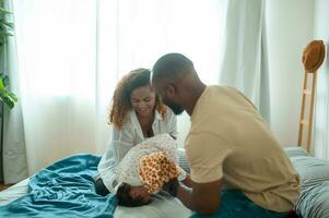 content africain américain Parents avec peu filles en jouant sur le lit dans chambre à maison, content famille concept photo