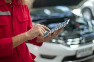 fermer technicien homme main en utilisant tablette en cours d'analyse voiture problèmes dans auto réparation magasin . concept de auto réparation et entretien service. photo