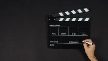 noir clap ou taper planche ou film ardoise avec droite main en portant stylo utilisation dans vidéo production ,film, cinéma industrie sur noir Contexte. photo