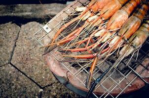 Accueil cuisiniers sont grillage crevettes sur une charbon poêle. photo