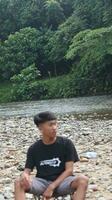 gorontalo-indonesie, mai 2023 - Jeune homme profiter le Matin atmosphère par le au bord de la rivière photo