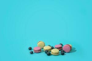 coloré français macarons et myrtilles sur une bleu Contexte photo