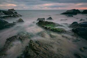 spectaculaire nuageux le coucher du soleil paysage de rocheux à sauvage atlantique chemin, algue plage dans comté Galway, Irlande photo