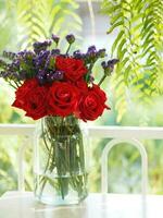 rose rouge et fleur de statice séchée rose tendre, couleur violette dans un vase en verre clair style vintage, concept pour écrire la conception de texte en arrière-plan avant photo