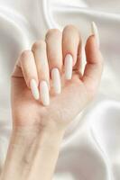 une femme mains avec une manucure sur eux, le ongles sont peint dans une blanc couleur. photo