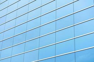 partie de une moderne verre bâtiment, un aluminium façade cette reflète le bleu ciel. photo