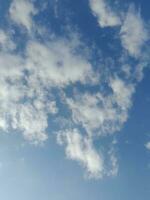 nuages blancs dans le ciel bleu. beau fond bleu clair. peu nuageux, beau temps. nuages bouclés par une journée ensoleillée. photo