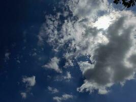 nuages blancs dans le ciel bleu. beau fond bleu clair. peu nuageux, beau temps. nuages bouclés par une journée ensoleillée. photo