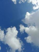 nuages blancs dans le ciel bleu. beau fond bleu clair. peu nuageux, beau temps. nuages bouclés par une journée ensoleillée. photo