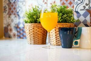 Orange jus dans une du vin verre est mis sur le table dans le cuisine. photo