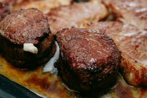 cuisine steaks dans une poêle. cuisine du boeuf à le culinaire Maître classe. le mains de le chef dans noir gants. photo