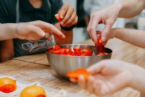 en train de préparer une dessert à une cuisine Maître classe. paniers avec les pêches et des fraises, Accueil cuisson. fermer, sélectif se concentrer. des pâtisseries, tartes avec les pêches de bouffée Pâtisserie. photo