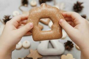 enfants mains tenir une pain d'épice dans le forme de une maison. le concept de Noël bonbons, jouets, guirlandes et bokeh. décor pour Nouveau année vacances. photo