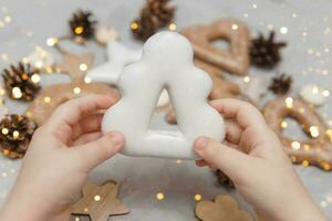 enfants mains tenir une pain d'épice dans le forme de une Noël arbre. le concept de Noël bonbons, jouets, guirlandes et bokeh. décor pour Nouveau année vacances. photo